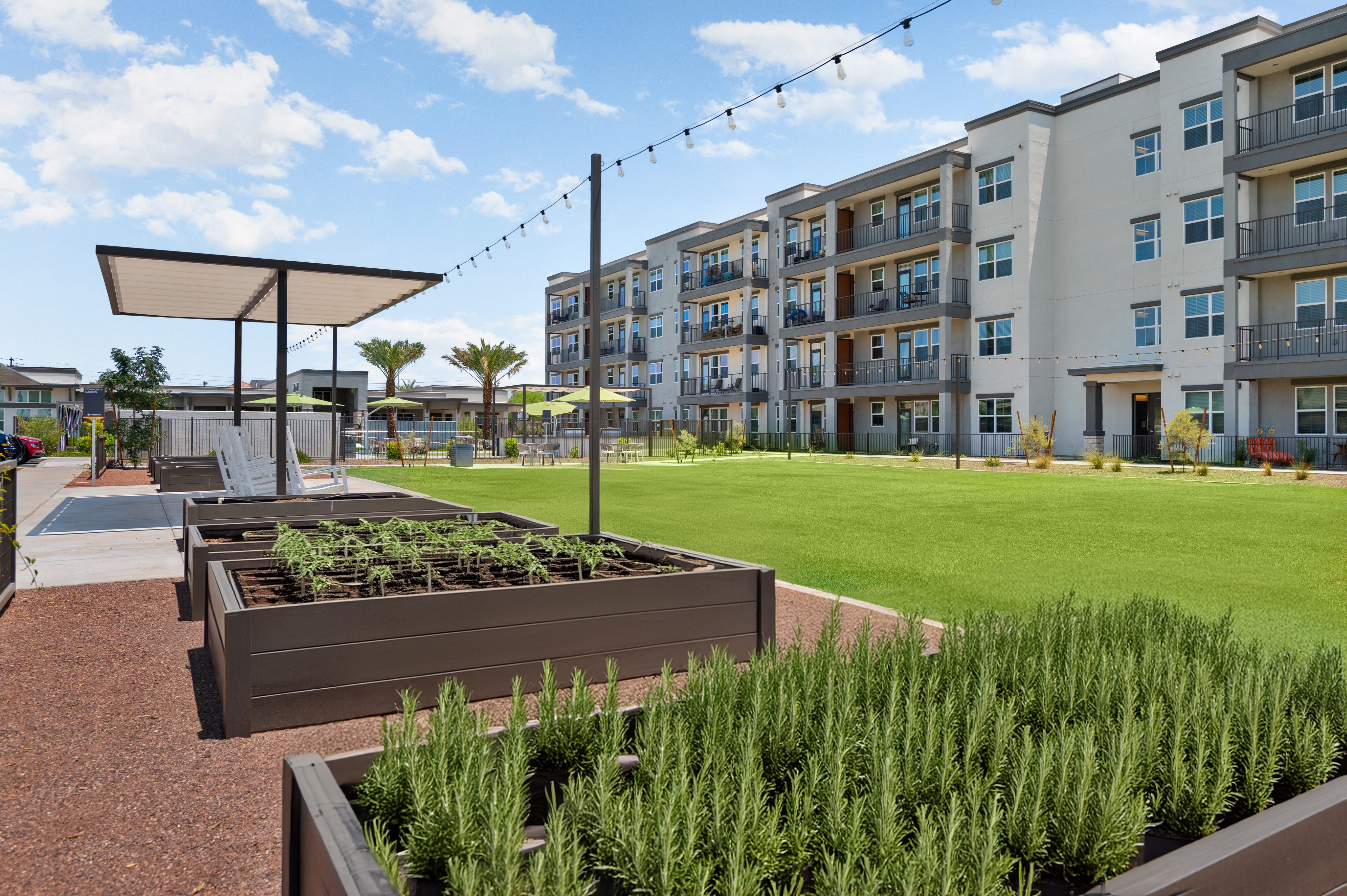 an exterior view of an apartment building with a lawn and garden